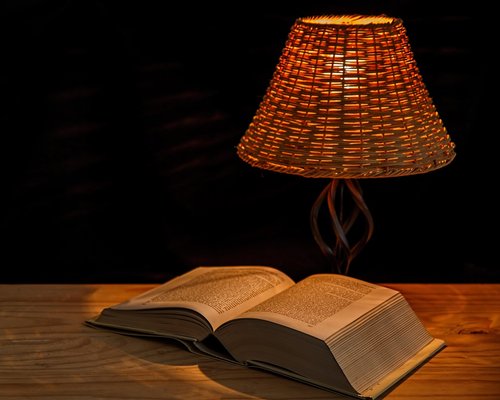A desk lamp providing warm, cozy illumination over an open notebook